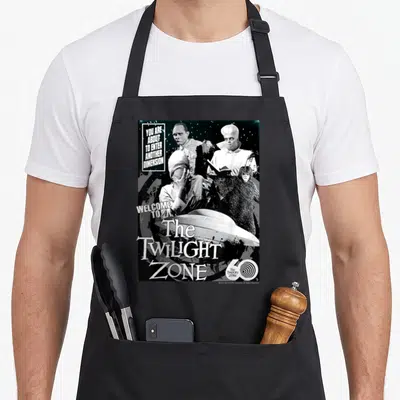 Zone twilight apron - Black and white Twilight Zone collage with characters UFO and anniversary 60 logo — shown on a black cotton canvas apron against a white background