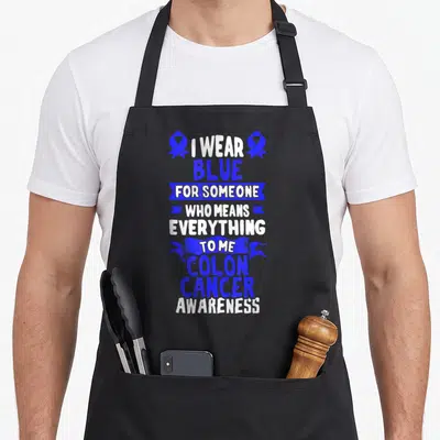 Crc patient apron - Stacked blue and white text reading I wear blue for someone who means everything to me colon cancer — shown on a black cotton canvas apron against a white background