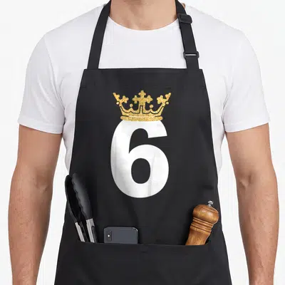 6th prince birthday apron - Gold glitter crown sitting atop a large white number 6 — shown on a black cotton canvas apron against a white background