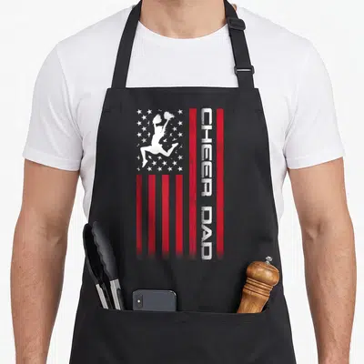 Cheer 4th of july apron - Vertical flag design with cheerleader silhouette and vertical CHEER DAD text on red stripes — shown on a black cotton canvas apron against a white background