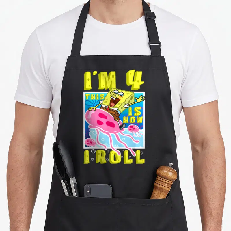 Roll birthday apron - SpongeBob riding pink jellyfish with text I'M 4 THIS IS HOW I ROLL in yellow and blue — shown on a black cotton canvas apron against a white background