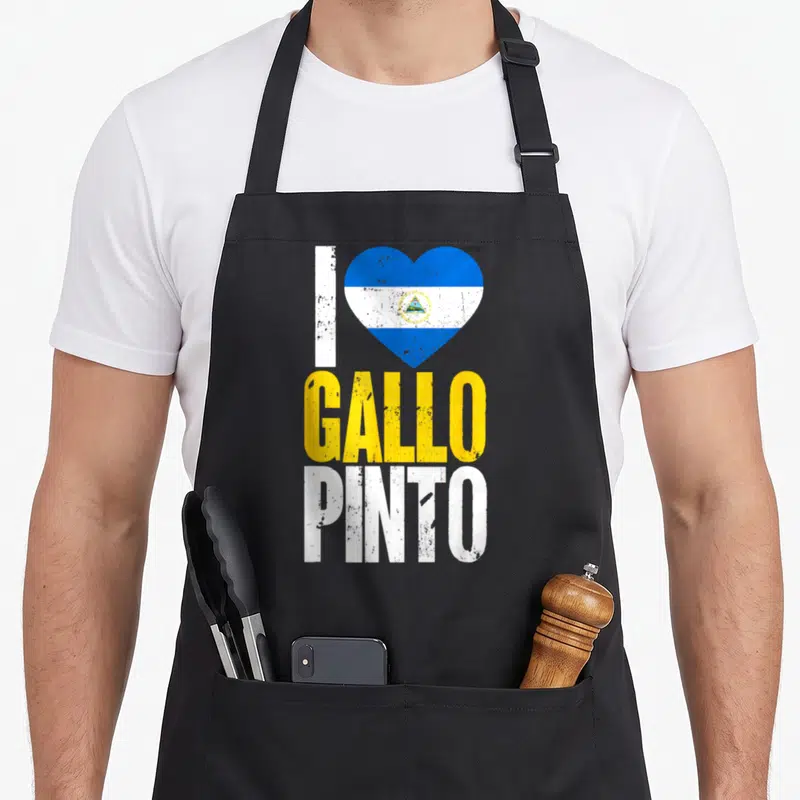 Gallo nicaraguan girl apron - Retro heart with blue white stripes and yellow white I GALLO PINTO text — shown on a black cotton canvas apron against a white background