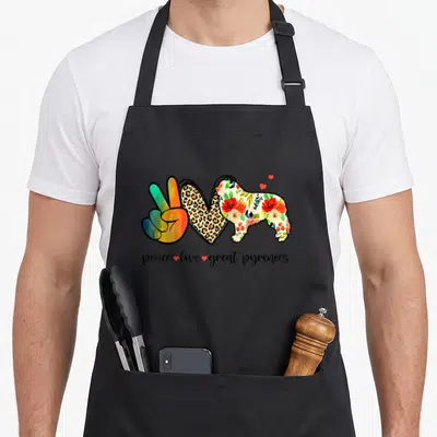 Peace pyrenee dog apron - Rainbow peace hand, leopard heart, floral dog silhouette, and script text with small red — shown on a black cotton canvas apron against a white background