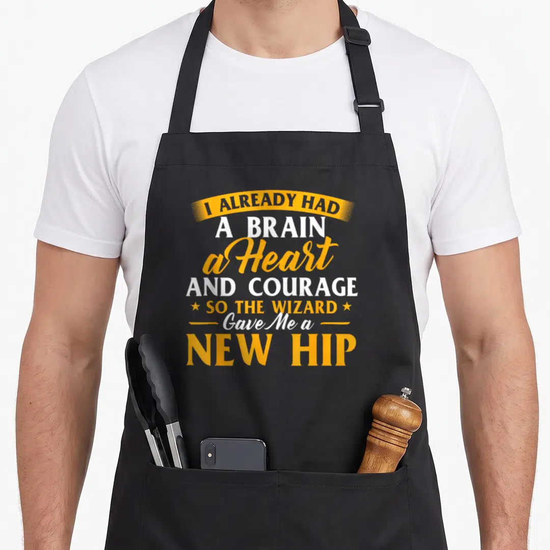 Wizard hip apron - I Already Had A Brain A Heart And Courage So The Wizard Gave Me A New Hip text design — shown on a black cotton canvas apron against a white background