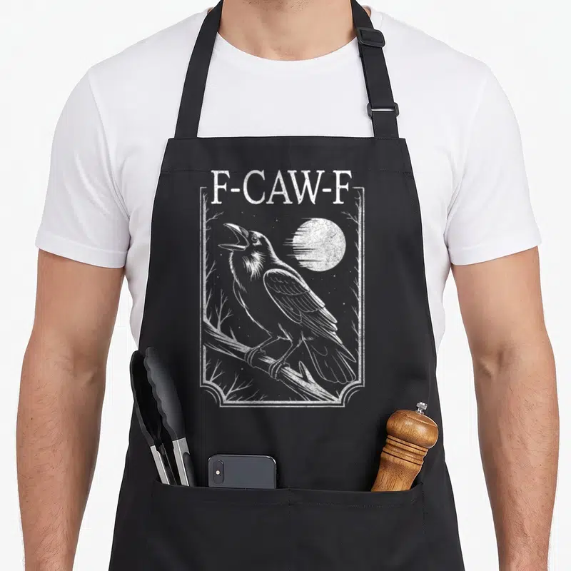 Minimal gothic apron - Distressed white crow perched on branch below F-CAW-F text inside rectangular frame — shown on a black cotton canvas apron against a white background