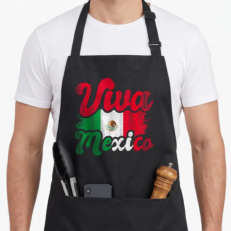 Viva mexican apron - Viva Mexico script over distressed green white red flag with eagle emblem — shown on a black cotton canvas apron against a white background