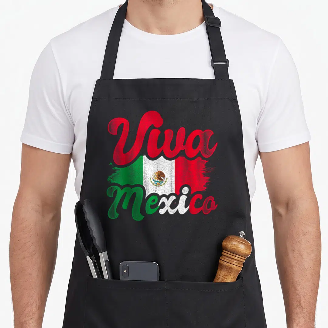 Viva mexican apron - Viva Mexico script over distressed green white red flag with eagle emblem — shown on a black cotton canvas apron against a white background