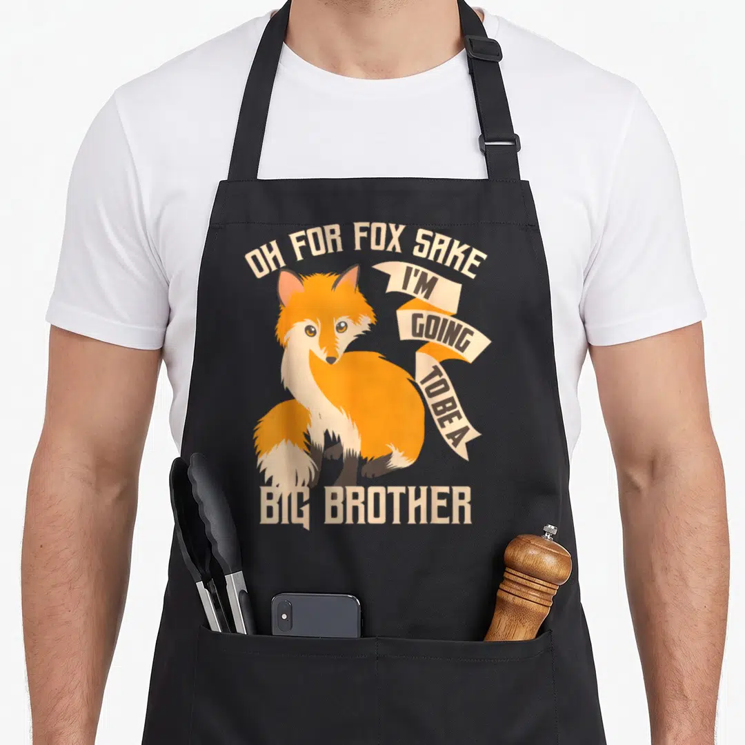 Sake fox mom apron - Cartoon fox with Oh For Fox Sake I'm Going To Be A Big Brother text — shown on a black cotton canvas apron against a white background