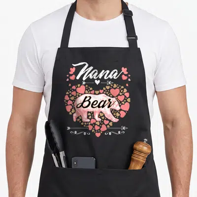 Nana mother's day aprons - Nana text above bear inside pink and tan heart graphic — shown on a black cotton canvas apron against a white background