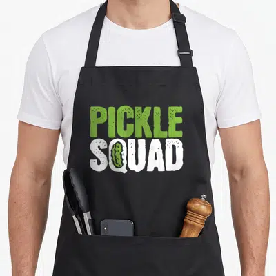 Cucumber pickle apron - Green PICKLE and white SQUAD text with a small pickle inside the letter U — shown on a black cotton canvas apron against a white background