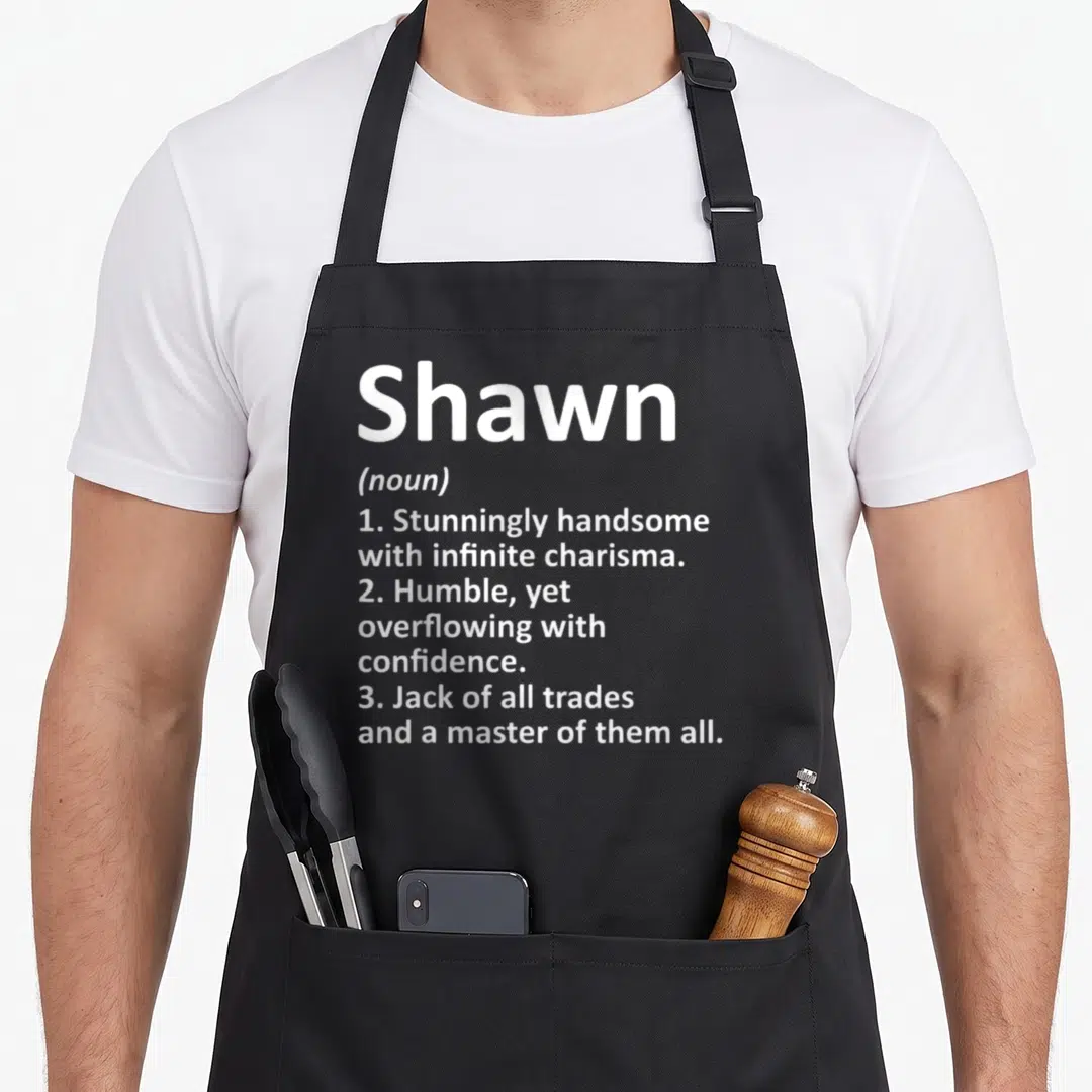 Shawn father day aprons - White text definition of Shawn as handsome confident and master of trades — shown on a black cotton canvas apron against a white background