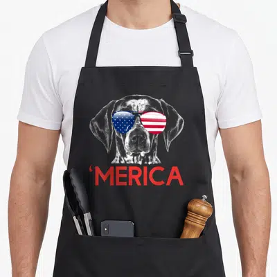 Shorthaired american flag apron - Realistic dog head with red white blue flag sunglasses and red MERICA text — shown on a black cotton canvas apron against a white background