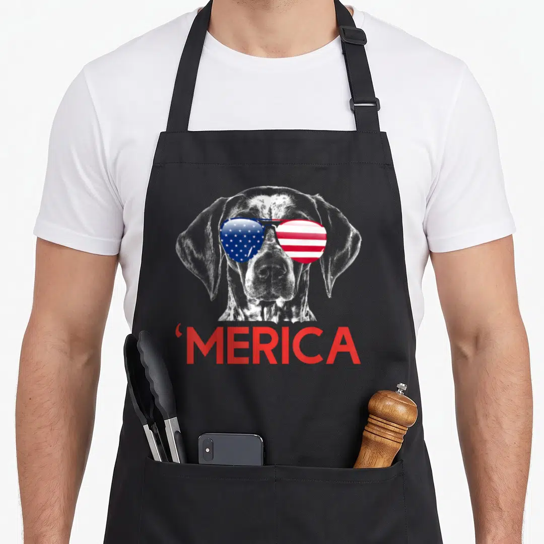 Shorthaired american flag apron - Realistic dog head with red white blue flag sunglasses and red MERICA text — shown on a black cotton canvas apron against a white background