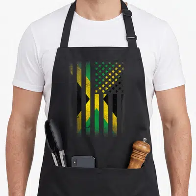 Jamaican american flag apron - Vertical green yellow black striped flag with distressed star field pattern — shown on a black cotton canvas apron against a white background