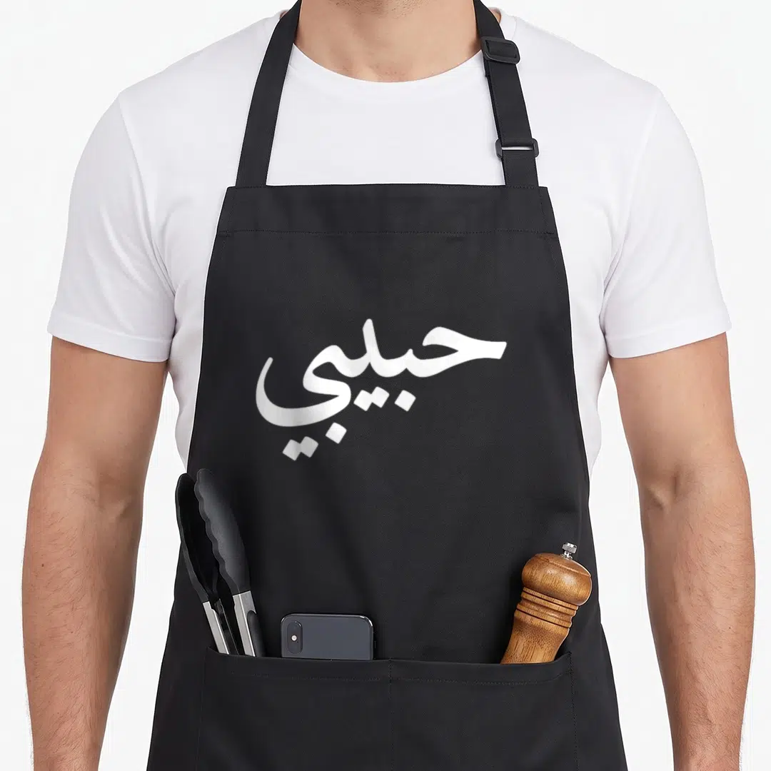 Arabic letter arab apron - White Arabic calligraphy reading Habibi centered on gray background — shown on a black cotton canvas apron against a white background