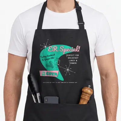 Parody nurse apron - Retro teal and pink ER Special diner menu with sandwich and ginger ale art — shown on a black cotton canvas apron against a white background