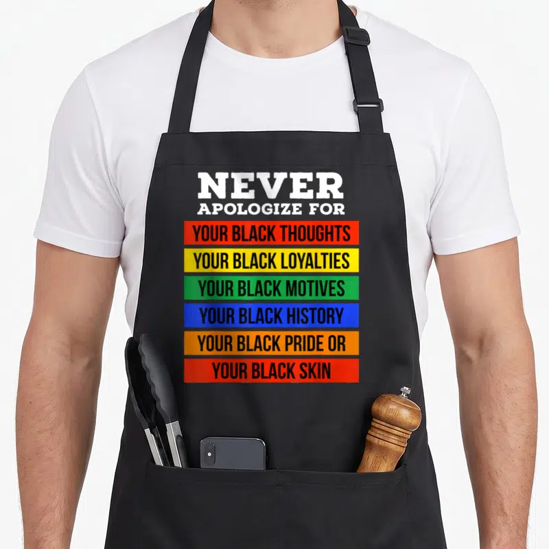 Apologize black history apron - Stacked text in red yellow green blue orange blocks reading Never Apologize For Your — shown on a black cotton canvas apron against a white background
