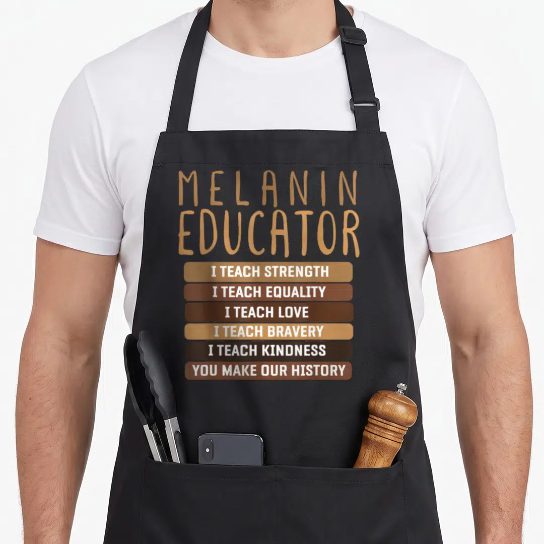 Dope teacher apron - MELANIN EDUCATOR text in tan above six brown bars with white phrases about teaching values — shown on a black cotton canvas apron against a white background