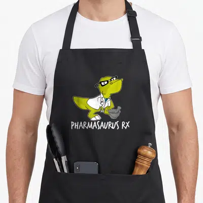 Pharmacy pharmacist apron - Lime green cartoon dinosaur in white coat with mortar pestle and PHARMASAURUS RX text — shown on a black cotton canvas apron against a white background