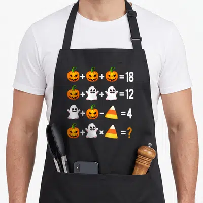 Operation pumpkin apron - Four rows of math equations with pumpkins, ghosts, and candy corn resulting in 18, 12, 4 — shown on a black cotton canvas apron against a white background