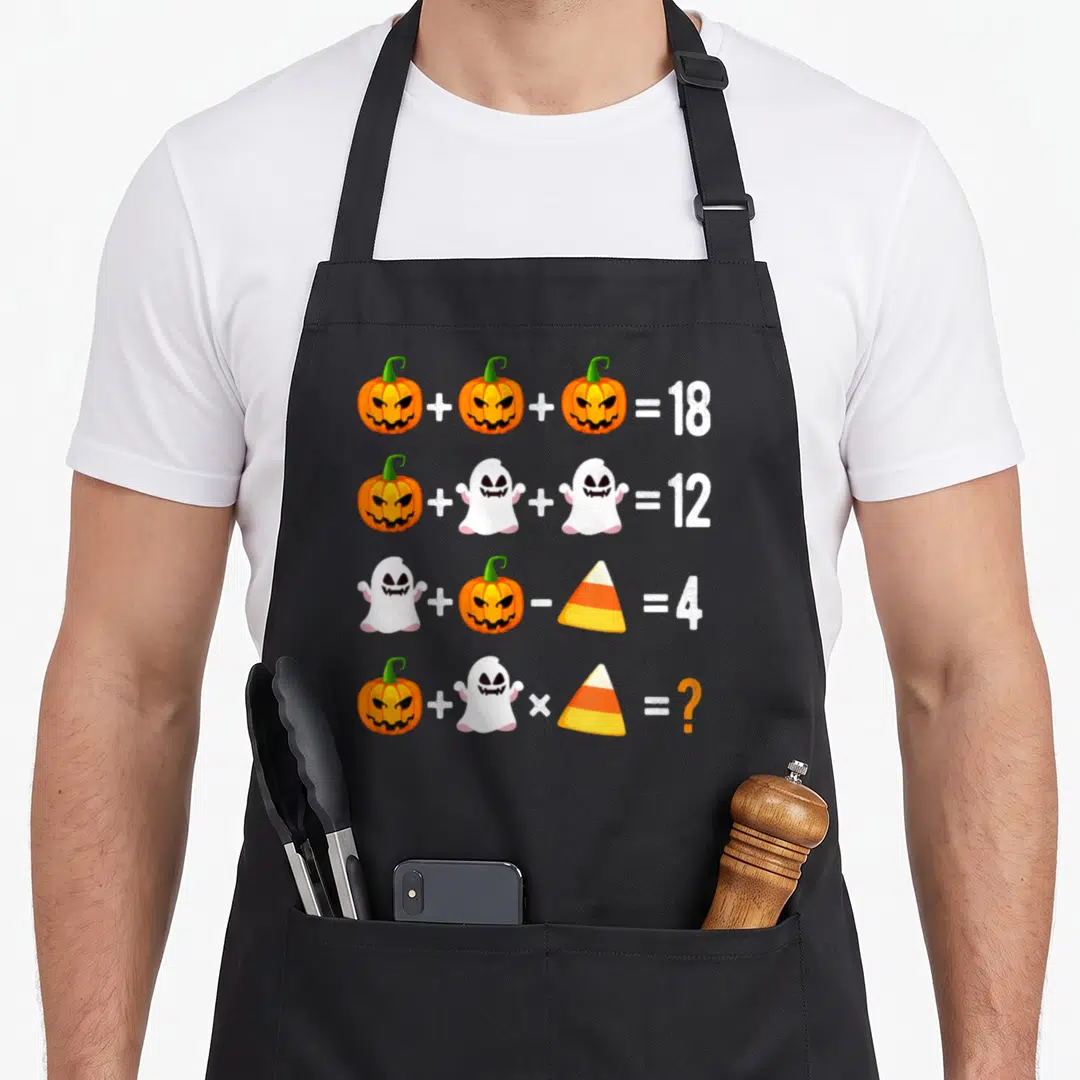 Operation pumpkin apron - Four rows of math equations with pumpkins, ghosts, and candy corn resulting in 18, 12, 4 — shown on a black cotton canvas apron against a white background
