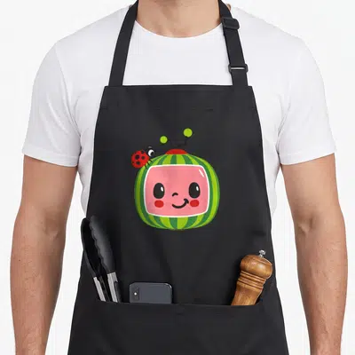 Smiling ladybug apron - Watermelon cartoon face with pink center, green stripes, and red ladybug perched on top — shown on a black cotton canvas apron against a white background