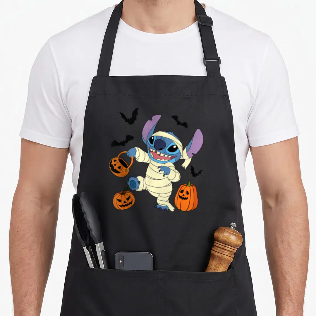 Cute halloween mummy and me aprons - Blue mummy character holding orange pumpkin bucket surrounded by four black bats — shown on a black cotton canvas apron against a white background