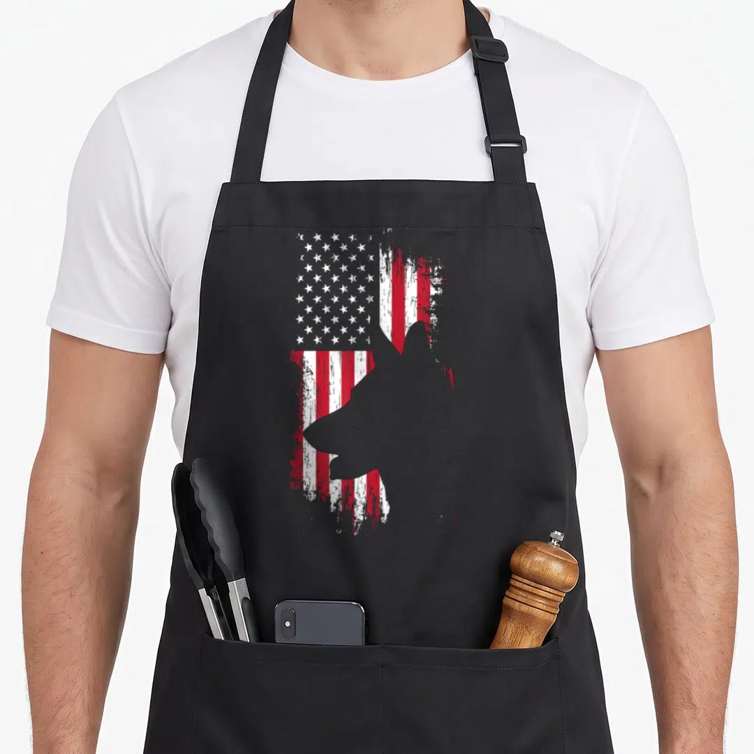 Shepherd american flag apron - Grey dog silhouette superimposed on a distressed red and white striped flag with white — shown on a black cotton canvas apron against a white background