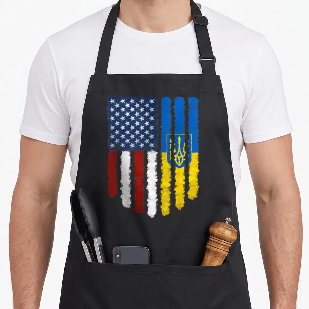 Ukrainian american flag apron - Watercolor merged US and Ukraine flags with stars and trident in blue red white — shown on a black cotton canvas apron against a white background