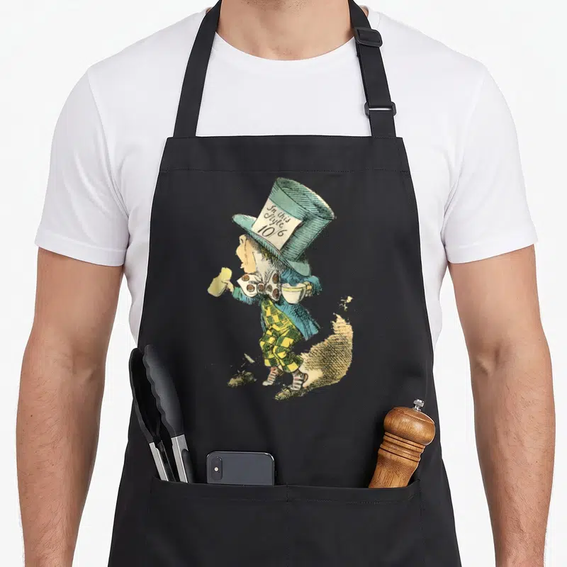 Illustration alice wonderland apron - Mad Hatter standing facing left holding teacup with In this Style 10/6 tag — shown on a black cotton canvas apron against a white background