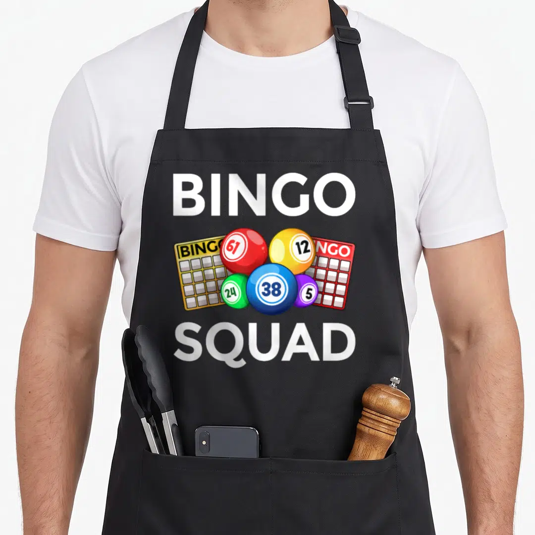 Player casino bingo apron - BINGO SQUAD text with colorful cartoon balls and two bingo cards on black apron — shown on a black cotton canvas apron against a white background