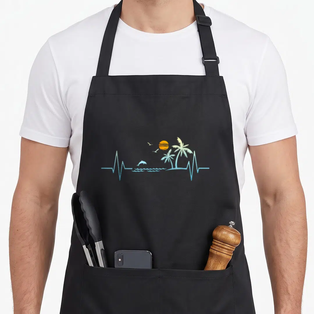 Heartbeat kitchen island apron - Minimalist blue heartbeat line forming waves, dolphin, two birds, orange sun — shown on a black cotton canvas apron against a white background