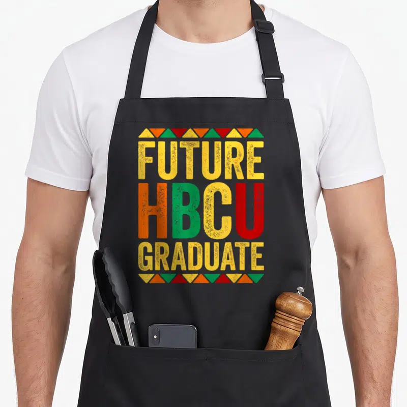 Future historical aprons - Stacked FUTURE HBCU GRADUATE text in yellow orange green red with triangle borders — shown on a black cotton canvas apron against a white background