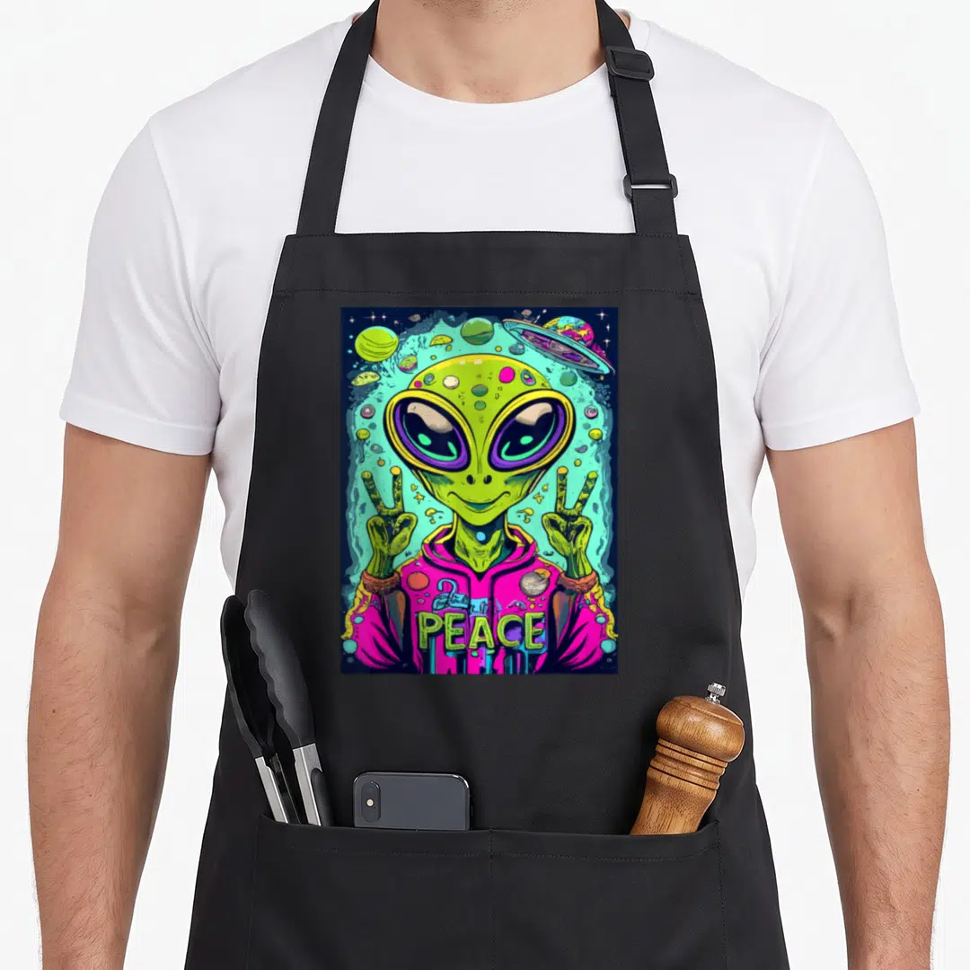 Funny abduction alien ufo apron - Green alien in pink hoodie making double peace signs with planets and UFO — shown on a black cotton canvas apron against a white background