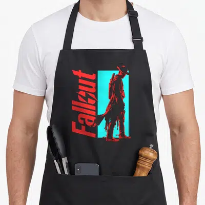 Shadow character aprons - Vertical red Fallout text beside a red figure standing against a cyan rectangle — shown on a black cotton canvas apron against a white background