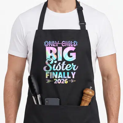 Expire big sister apron - Tie-dye text crossing out ONLY CHILD with BIG Sister finally 2026 arrows — shown on a black cotton canvas apron against a white background