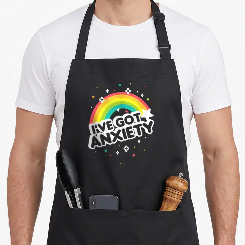 Lookhuman nerd apron - Cartoon rainbow in white red yellow green blue over stacked I've Got Anxiety text surrounded — shown on a black cotton canvas apron against a white background