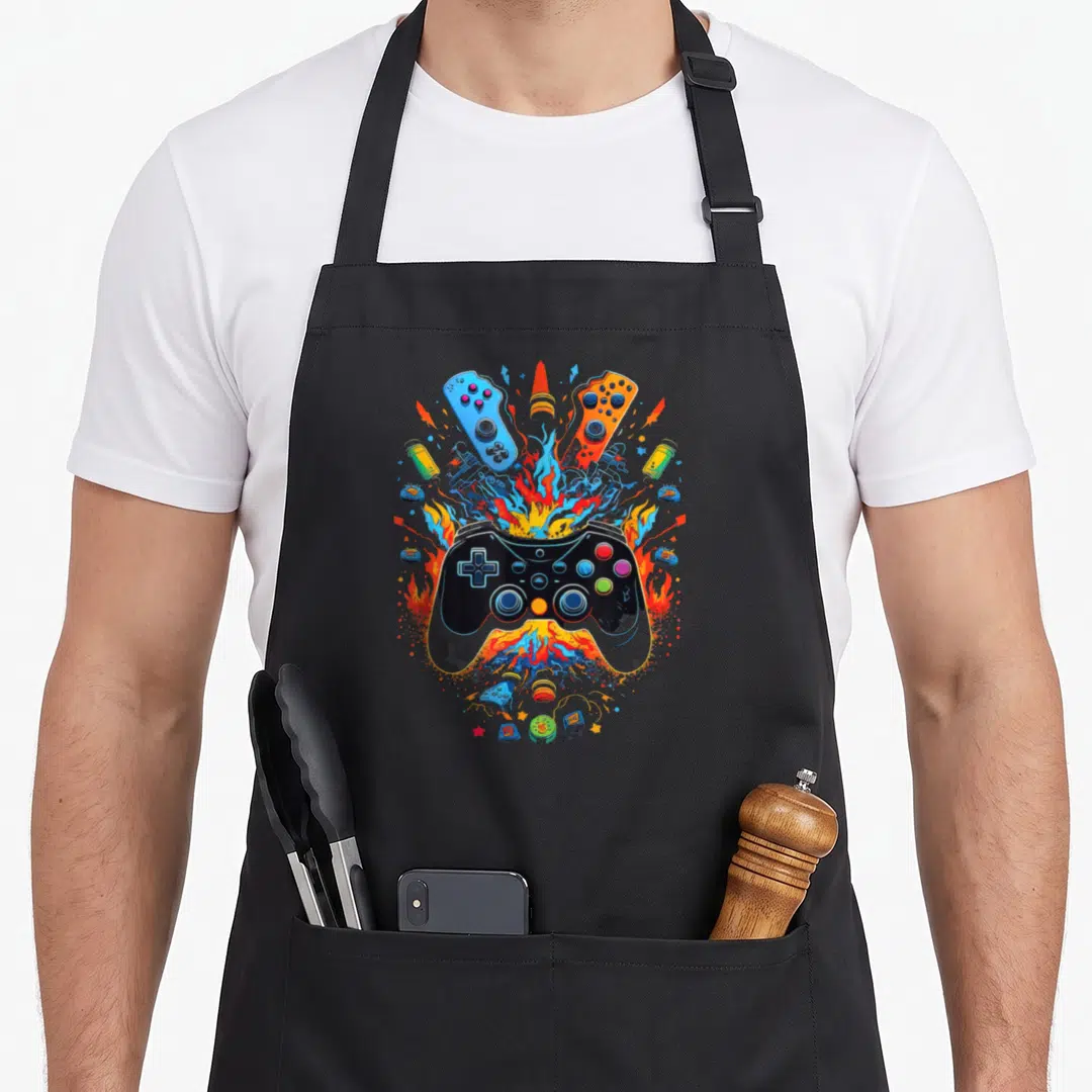 Vintage gaming video game apron - Black controller with blue orange fire and peripherals cartoon explosion — shown on a black cotton canvas apron against a white background
