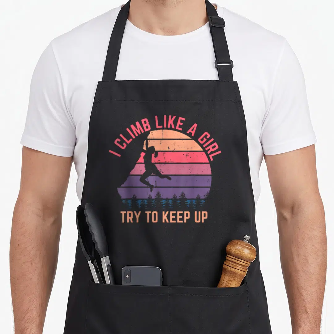 Try climbing apron - Retro sunset with climber silhouette and I climb like a girl text — shown on a black cotton canvas apron against a white background