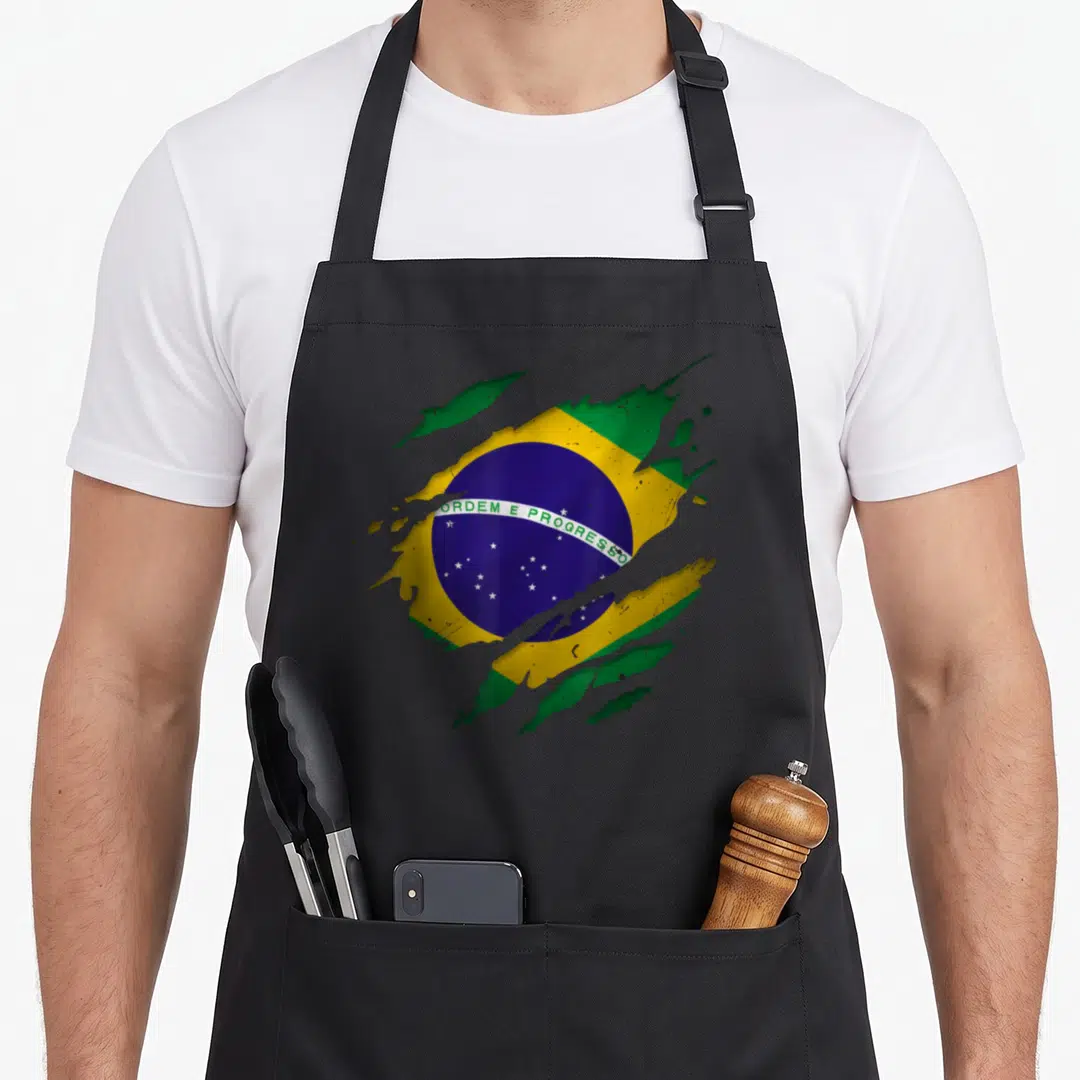 Proud torn apron - Brazilian flag appearing through a torn surface with green yellow blue colors and text ORDEM E — shown on a black cotton canvas apron against a white background