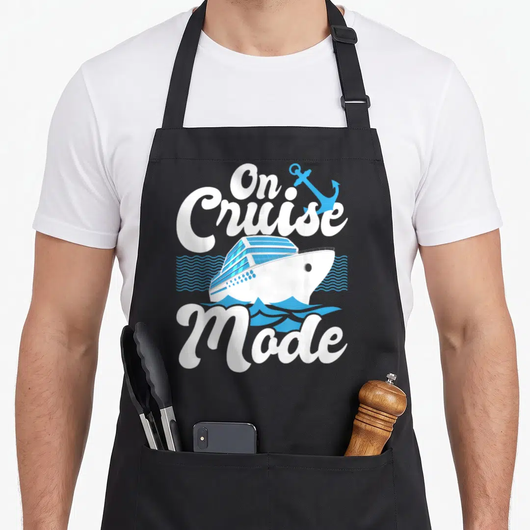 Mode cruising apron - On Cruise Mode text with white blue ship anchor and waves — shown on a black cotton canvas apron against a white background