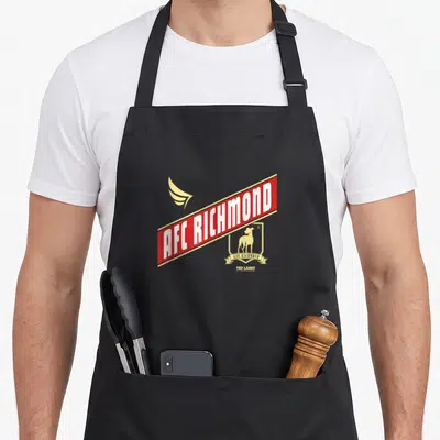Crossed richmond apron - AFC Richmond red banner gold wing shield dog logo TED LASSO minimalist print — shown on a black cotton canvas apron against a white background