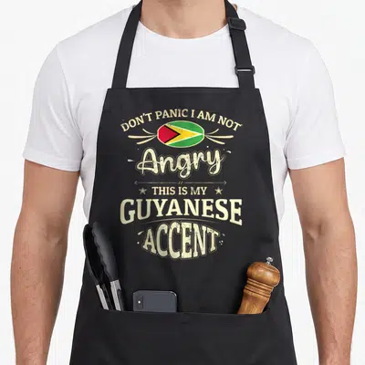 Funny guyana guatemalan aprons - Distressed Guyana flag and text Don't Panic I Am Not Angry This Is My Guyanese Accent — shown on a black cotton canvas apron against a white background