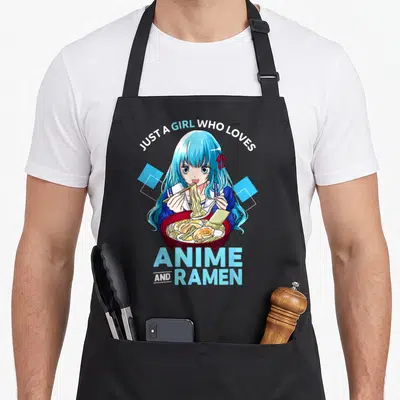 Ramen bowl anime apron - Blue hair anime girl eating ramen with arched text JUST A GIRL WHO LOVES — shown on a black cotton canvas apron against a white background