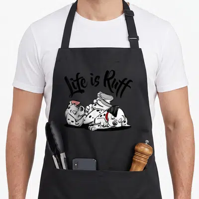 Ruff dalmatian apron - Life is Ruff text above spotted puppy lying on back with red collar — shown on a black cotton canvas apron against a white background