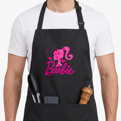 General apron for dad - Pink Barbie silhouette filled with hearts above script text — shown on a black cotton canvas apron against a white background