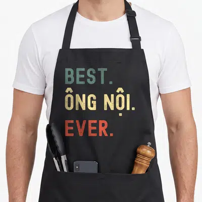 Ong grandpa apron - Distressed stacked text reading BEST. ÔNG NỘI. EVER. in teal, beige, and orange-red — shown on a black cotton canvas apron against a white background