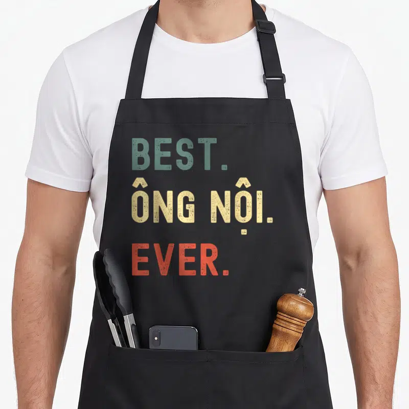 Ong grandpa apron - Distressed stacked text reading BEST. ÔNG NỘI. EVER. in teal, beige, and orange-red — shown on a black cotton canvas apron against a white background