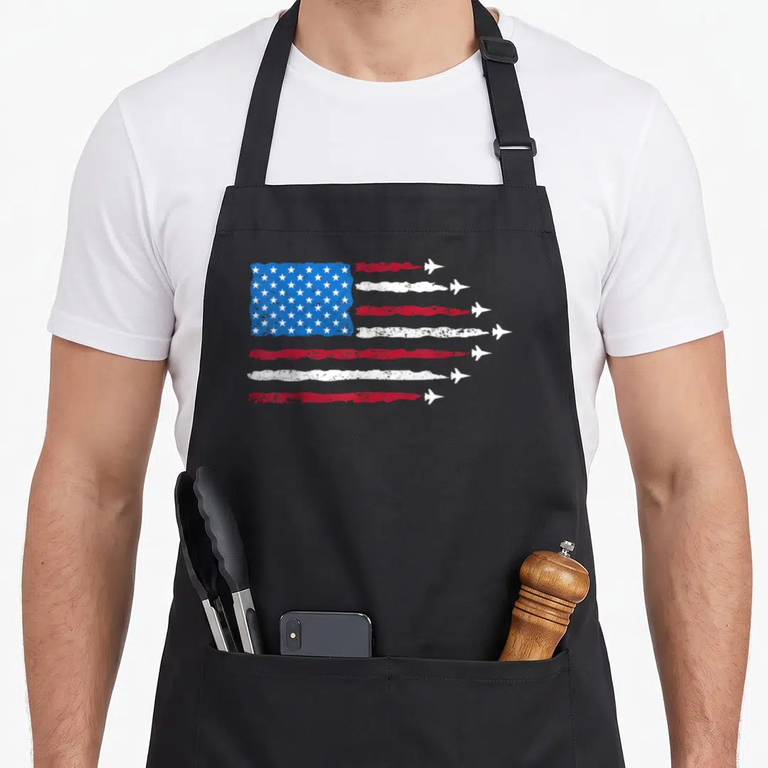 Patriotic blue 4th of july apron - Distressed USA flag with red and white stripes ending in white jet planes on a blue — shown on a black cotton canvas apron against a white background