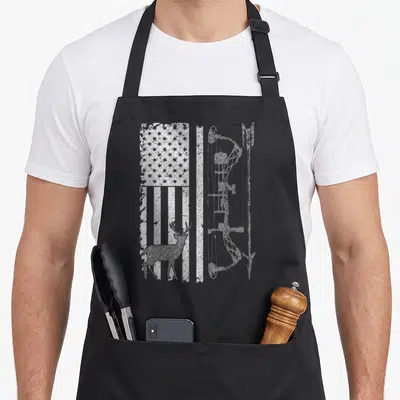 Hunting grill hunter apron - Distressed white USA flag, deer silhouette, and vertical bow printed on black fabric — shown on a black cotton canvas apron against a white background